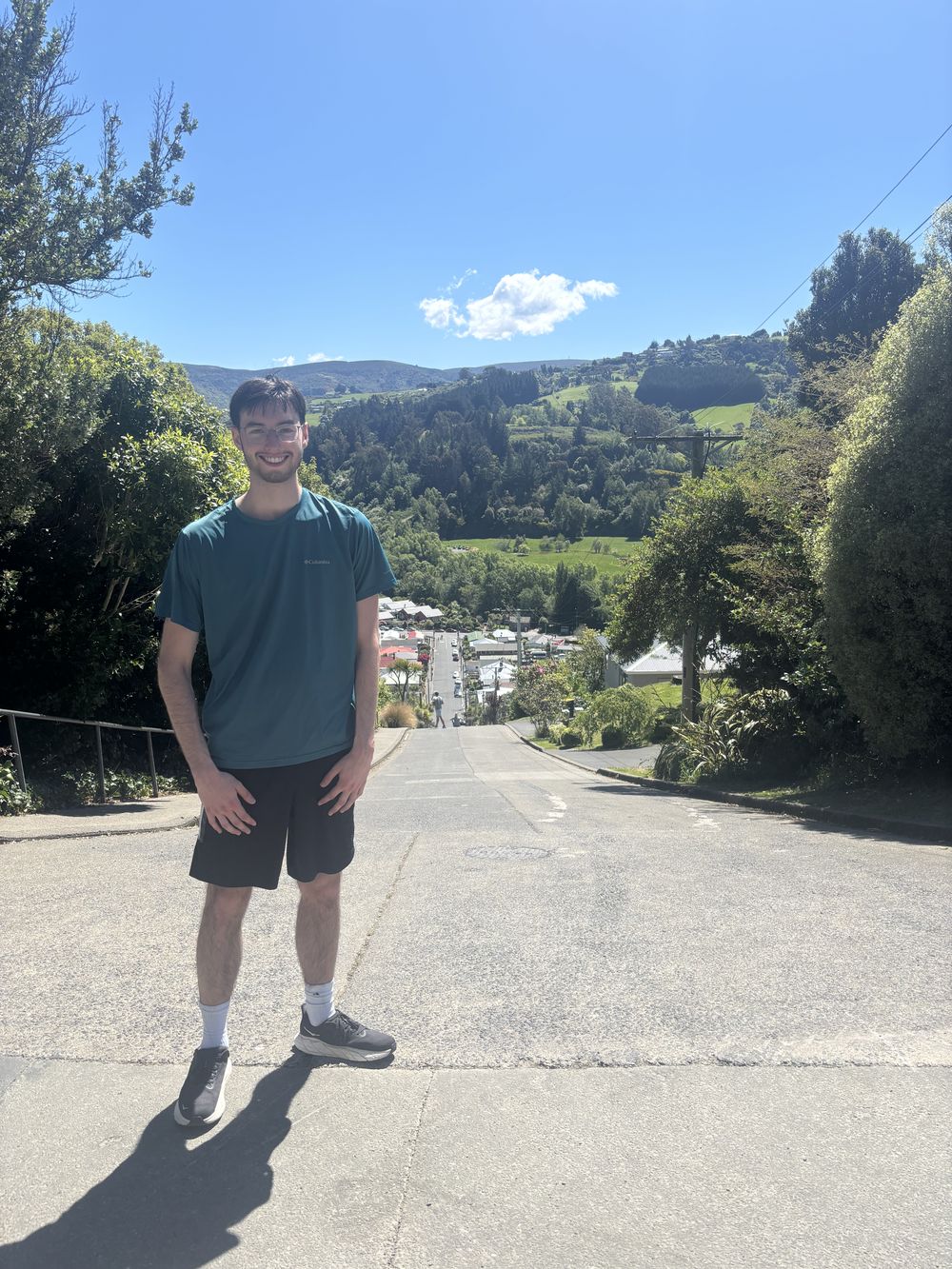 Todd standing at the top of Baldwin Street in Dunedin, New Zealand, with green hills behind him